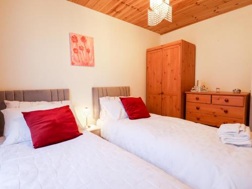 a bedroom with two beds with red pillows and a dresser at Kantankye Lodge in Skegness