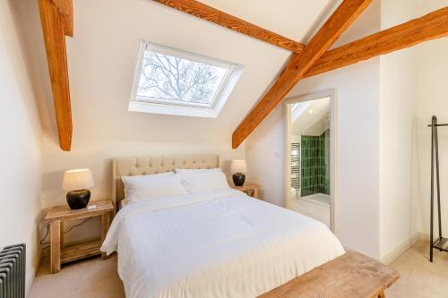 1 dormitorio con cama blanca y ventana en Ysgubor Maen Y Bardd en Conwy