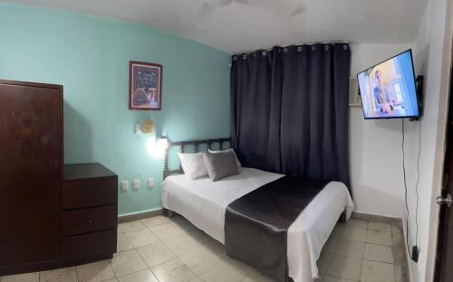 a bedroom with a bed and a flat screen tv at Hotel Santa Barbara in Mazatlán