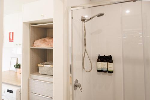 a shower in a bathroom with a glass door at Sweet beautiful TINY HOME with pool and 2 minute drive to the beach in Wollongong