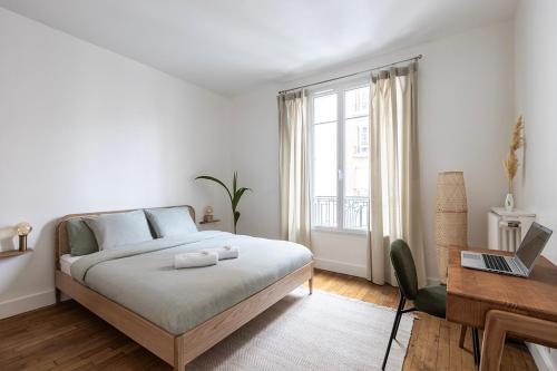 - une chambre avec un lit et un bureau avec un ordinateur portable dans l'établissement Nouveau T2 à 7 min de Saint-Lazare, à Asnières-sur-Seine