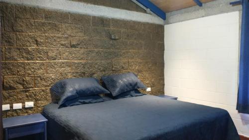 LONGO VI في San Antonio de las Alzanas: غرفة نوم بسرير وجدار من الطوب