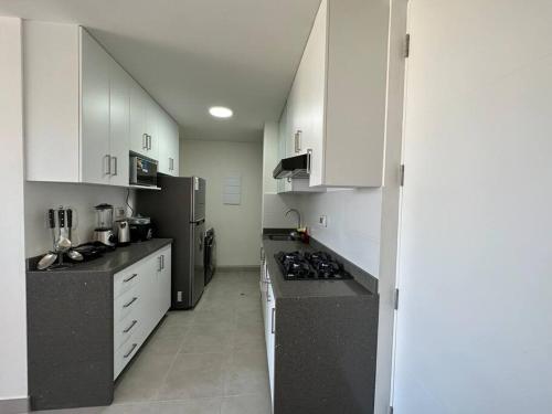 una cocina con armarios blancos y encimeras negras en Apartamento de estreno San Bartolo vista Piscina Playa, en San Bartolo