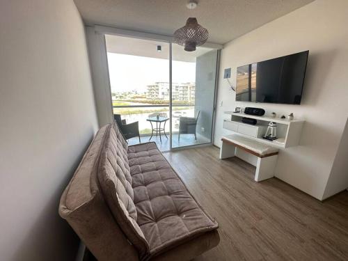 un soggiorno con divano, TV e tavolo di Apartamento de estreno San Bartolo vista Piscina Playa a San Bartolo