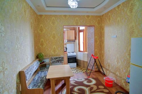 Habitación con mesa y cocina con papel pintado de color amarillo. en Однокомнатная в Душанбе en Dushanbe