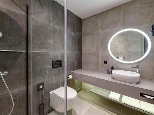 La salle de bains est pourvue de toilettes, d'un lavabo et d'un miroir. dans l'établissement ibis Styles Friedrichshafen, à Friedrichshafen