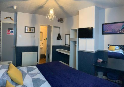 Hornby Villa 4*B&B Couples & Families Only في بلاكبول: غرفة نوم بسرير ومكتب وتلفزيون