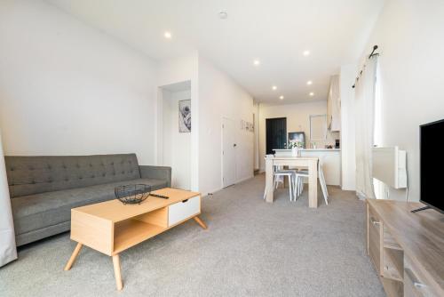 ein Wohnzimmer mit einem Sofa und einem Tisch in der Unterkunft Cozy Brand New Townhouse 2 in Auckland