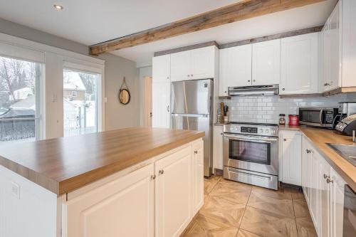 a kitchen with white cabinets and a wooden counter top at Breathtaking Lake View With Spa Chalet 360 in Chertsey
