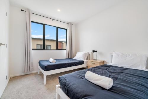 1 Schlafzimmer mit 2 Betten und einem Fenster in der Unterkunft Cozy Brand New Townhouse 3 in Auckland
