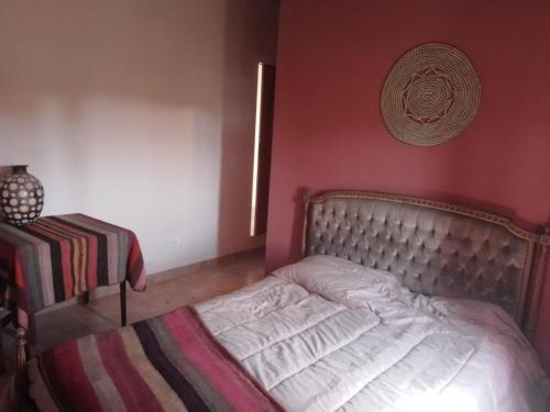 1 cama en un dormitorio con una pared roja en Chakana en Villa Yacanto
