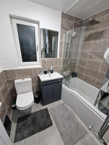 een badkamer met een toilet, een wastafel en een bad bij Pav's Den in Ince-in-Makerfield