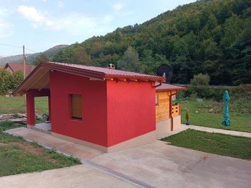a small red building with a mountain in the background at Milica 2 Mezdrejska 87 A in Crni Vrh