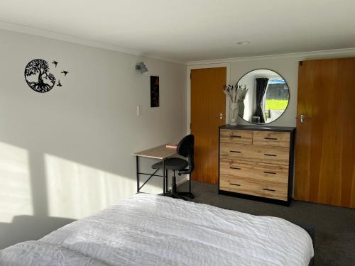 a bedroom with a bed and a desk and a mirror at Hill View Abode Tawa in Wellington