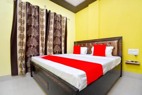 OYO Blue Sky Guest House في Kurukshetra: غرفة نوم بسرير كبير ومخدات حمراء