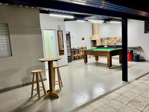 a room with a pool table and two stools at Casa aconchegante em Peruíbe in Peruíbe