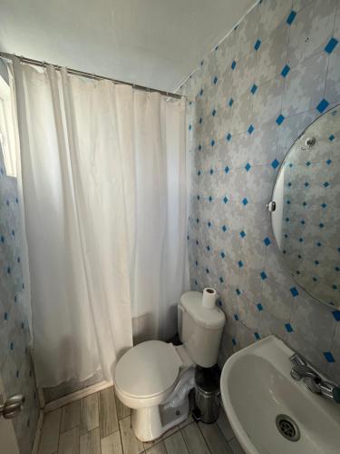 een badkamer met een toilet, een wastafel en een spiegel bij Casa Miramar in Quellón