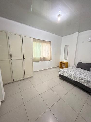 a white bedroom with a bed and a window at ARMANI in Puerto Colombia