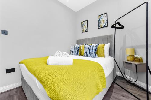 a bedroom with a bed with a yellow blanket at City Getaway- Newly Renovated Flat for Groups in Greenford
