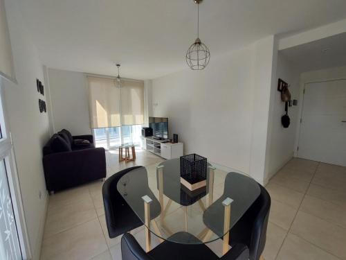 Messidor Mar del Plata Luminoso departamento 2 ambientes con cochera في مار ديل بلاتا: غرفة معيشة مع طاولة وكراسي زجاجية