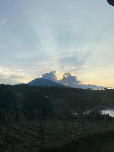 a sunset over a mountain with a river and trees at Myra Chalets in Bijagua
