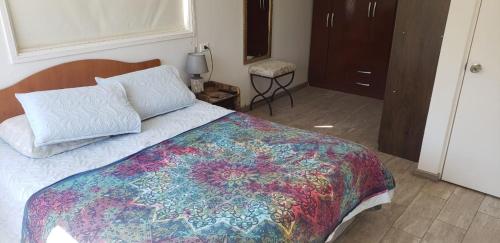 Un dormitorio con una cama con una colcha colorida. en Casa de Campo full equipada en San Vicente de Taguatagua
