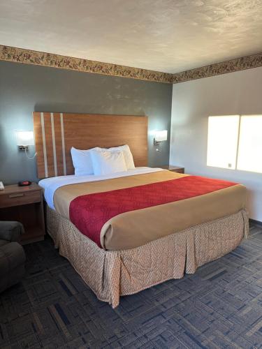 a bedroom with a large bed with a red blanket at Budget Host Inn Charleston in Charleston