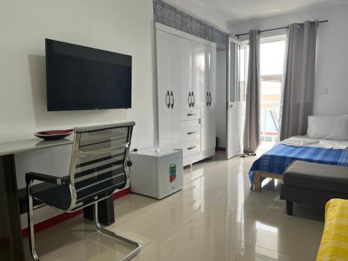 a bedroom with a bed and a desk with a television at Hotel Principal in Tarrafal