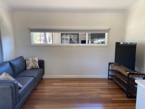 a living room with a blue couch and a television at Corowa Bindaree Holiday Park in Corowa