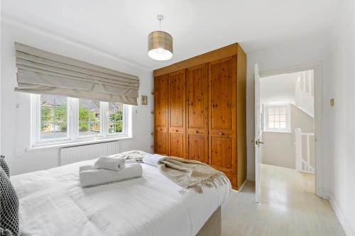 um quarto branco com uma cama grande e um armário de madeira em Huge Home by Station / Gym & Garden em Londres