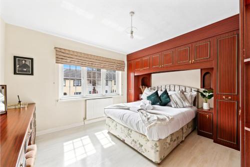 a bedroom with a large bed with a wooden headboard at Huge Home by Station / Gym & Garden in London