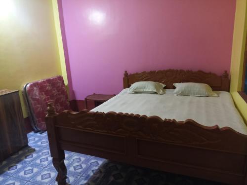 a bedroom with a wooden bed with pink walls at Niraloy in Bolpur