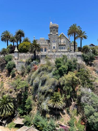 een oud huis op een heuvel met palmbomen bij Lechón Marina in Viña del Mar