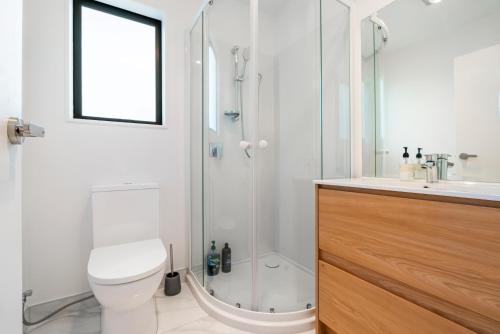 a bathroom with a shower and a toilet and a sink at Cozy Brand New Townhouse 20 in Auckland