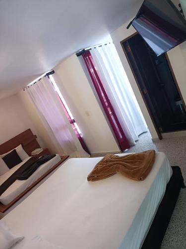 Una cama en una habitación con ventanas y una camisa. en Hotel Bicentenario Rionegro, en Rionegro