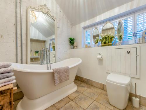 bagno bianco con vasca e servizi igienici di The Cottage a Hungerton