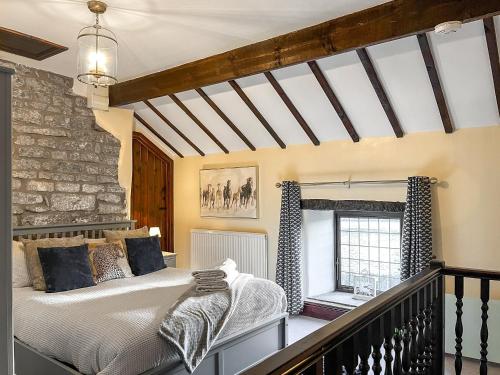 a bedroom with a bed and a stone wall at Sienna Cottage - W7764 in Monyash