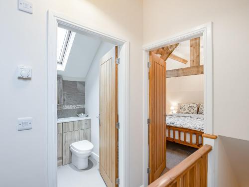 a bathroom with a toilet and a bed in a room at Northwood Farm Cottage in Marchamley