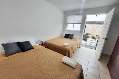 a bedroom with two beds and a door to a balcony at Centro histórico, tranquilo y con terraza in Querétaro