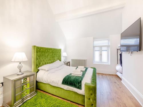 a bedroom with a large bed with a green headboard at Violet Cottage - Uk45968 in Yarm
