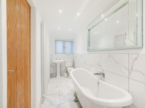 a white bathroom with a tub and a sink at Violet Cottage - Uk45968 in Yarm