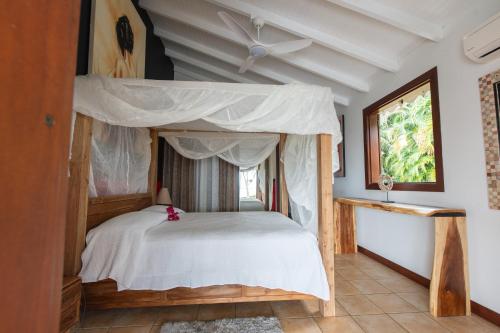 um quarto com uma cama de dossel e uma janela em Villa Créole Confortable avec vue sur lagon em Sainte-Rose