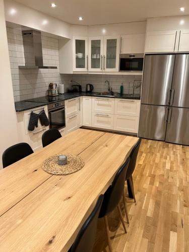 a kitchen with a wooden table and a refrigerator at Noah Longstay Apartment in Västerås