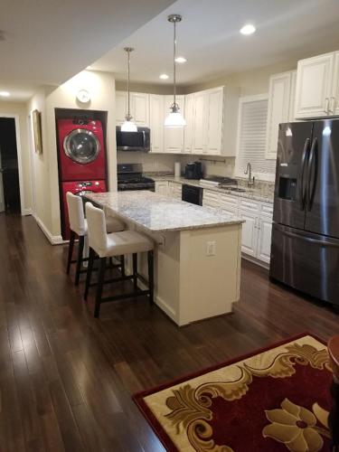 a kitchen with a large island with chairs and a refrigerator at Beautiful New 4 Bedroom 3 Bath Family Home Or 1 BR Apt Nr Howard U Downtown NW DC in Washington, D.C.