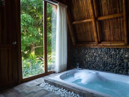 a bath tub in a room with a large window at Ecohabs Bamboo Parque Tayrona - Dentro del PNN Tayrona in El Zaino