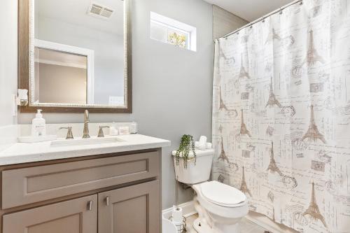 a bathroom with a toilet and a sink and a shower curtain at Amazing 3bedroom townhome, in Historic Dryade City in New Orleans