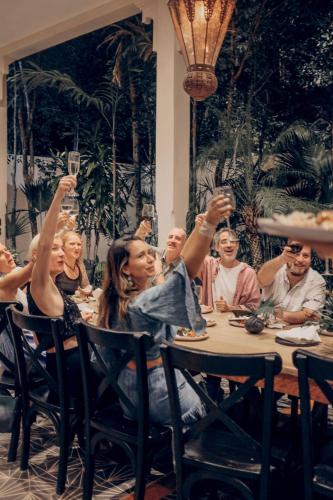 a group of people sitting at a table with their hands in the air at Yum Kaax Boutique Villa in Tulum