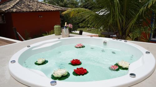a jacuzzi tub with four flowers in it at Hotel Liberdade Búzios in Búzios