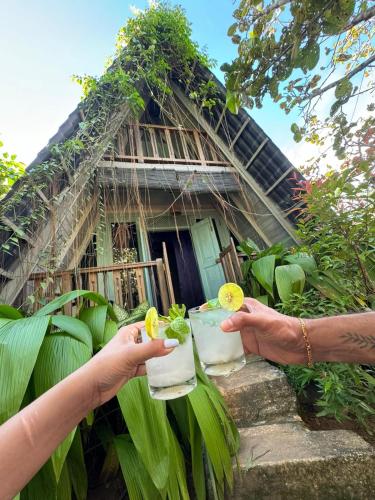 two people holding drinks in front of a house at villa ovita in Talpe