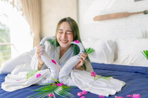 uma mulher sentada numa cama segurando dois pelicanos em Windy Seaview Resort em Praia de Chao Lao